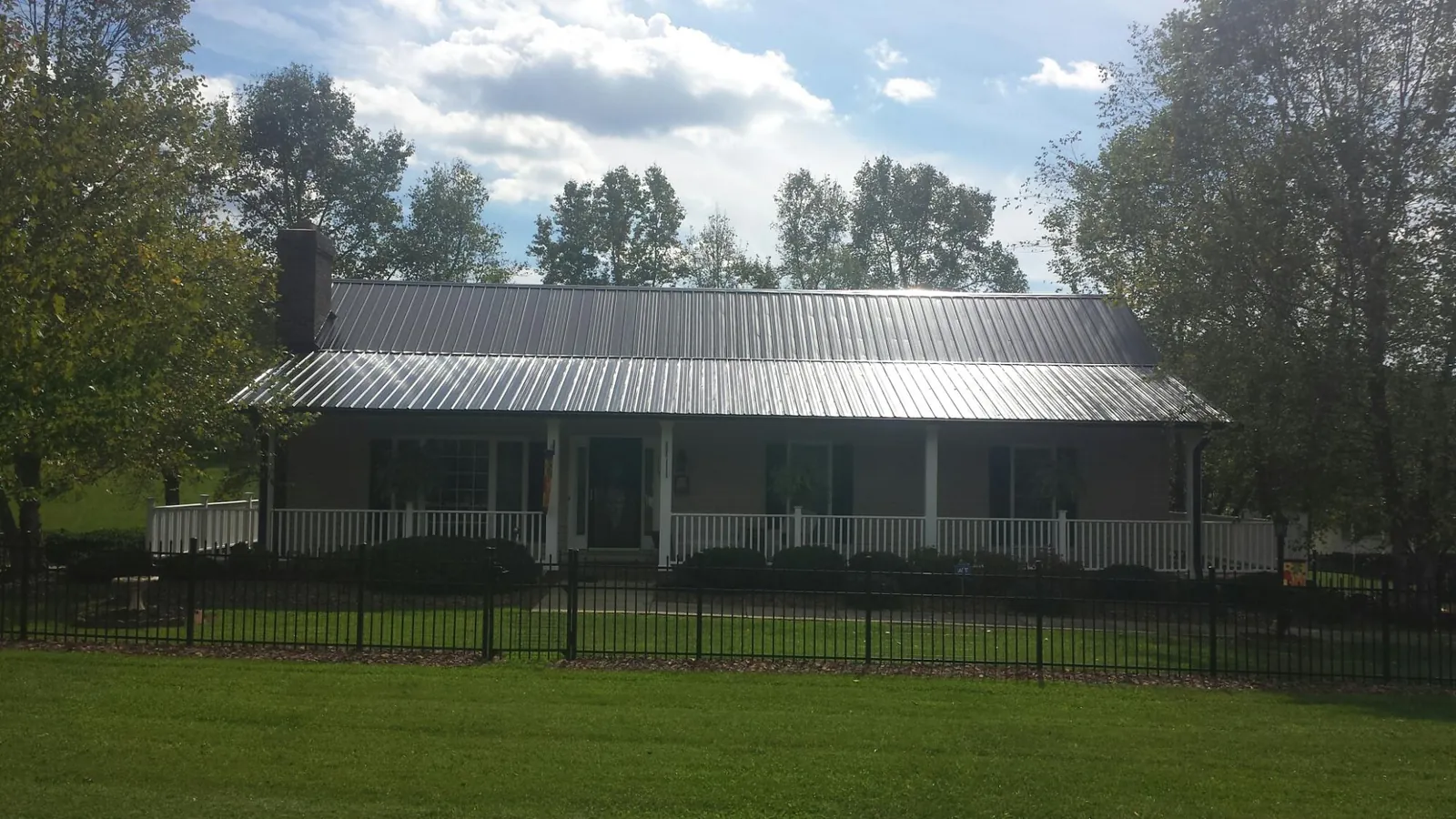 Gray metal roof on a brick ranch with a full width front porch — Gutter Guard Installation work by our crew in San Antonio